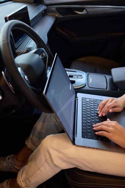 A person is working on a laptop inside a car during their commute to a destination