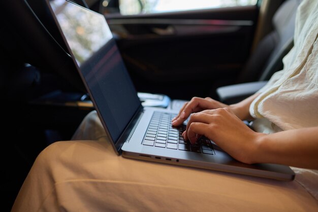 A person is working on a laptop inside a car during their commute to a destination