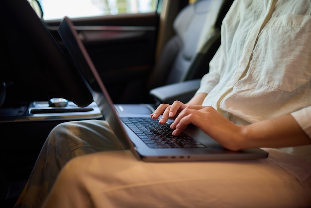 A person is working on a laptop inside a car during their commute to a destination