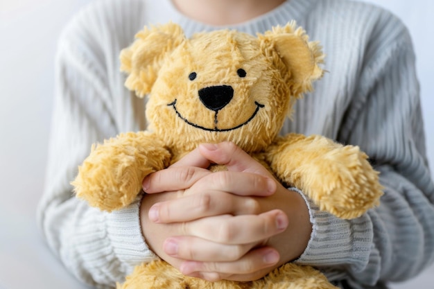 A person joyfully holds a yellow teddy bear in their hands