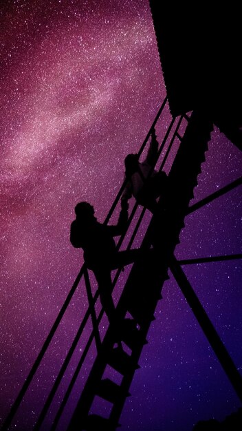 Photo a person on a ladder with the stars in the background