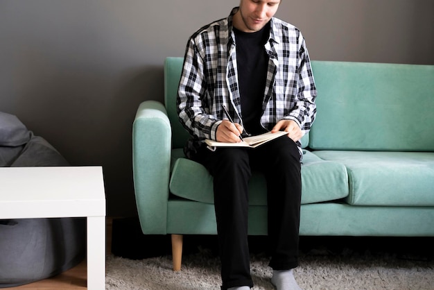 A person making notes in the book staying at home