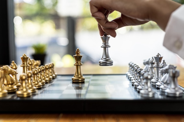 Person playing chess board game, business woman concept image holding chess pieces like business competition and risk management, planning business strategies to defeat business competitors.