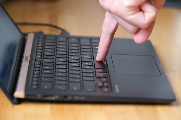 Person presses buttons on laptop keyboard with two fingers