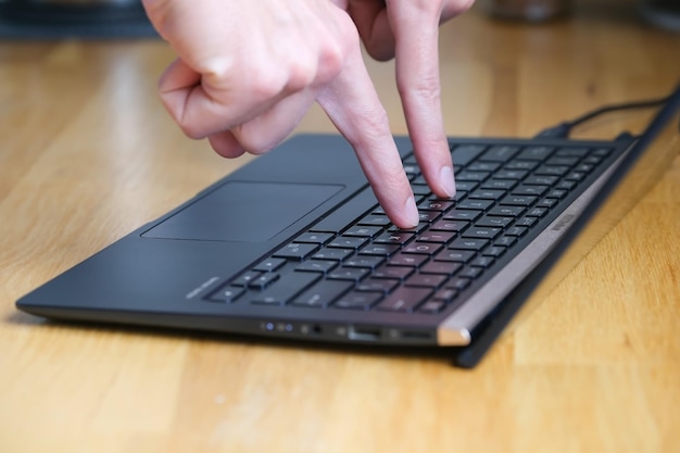 Person presses buttons on laptop keyboard with two fingers