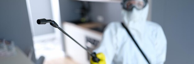 Photo person in protective suit and mask disinfects kitchen