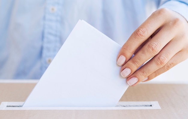 Person putting empty ballot in a box close-up