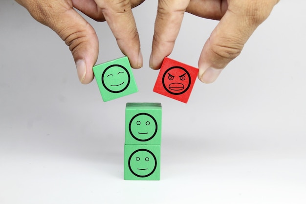 A person putting a green and red cube with a red square with a green square with a smiley face on it.