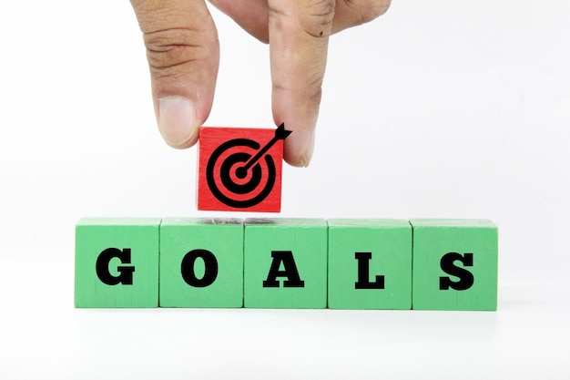 A person putting a red dart on a green cube that says goals.