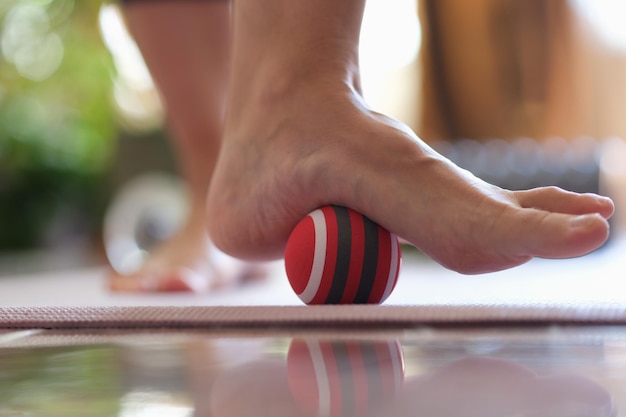 Person rolls ball on foot at home closeup