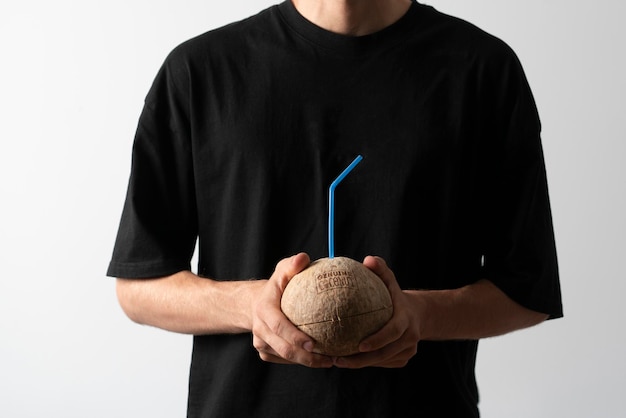 A person's hands holding a coconut with straw