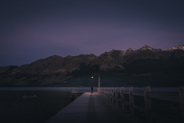 Person standing at the end of the dock at the lake