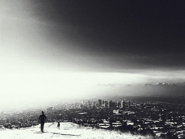 Photo person standing on field towards cityscape against sky during winter