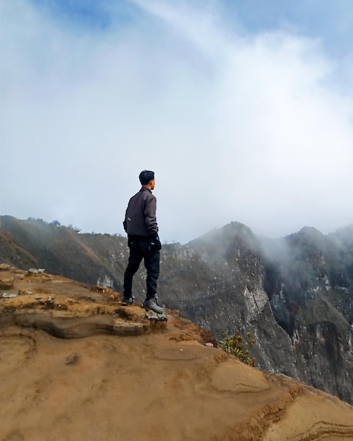 a person standing on the top of a mountain on the edge of a cliff 2