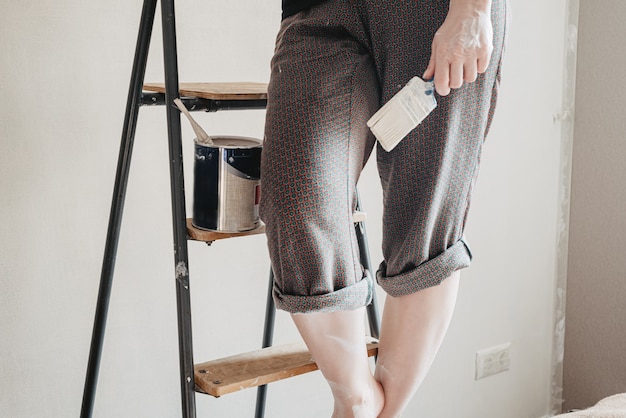 Person stands on stepladder holding brush in hand