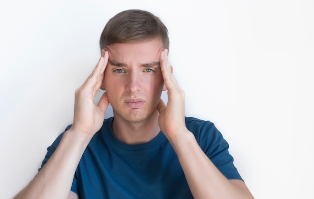 Person suffering from feeling pain because severe headache, migraine. Handsome nice guy, young annoyed upset man holding his head with hands, temples with fingers, . Face expression