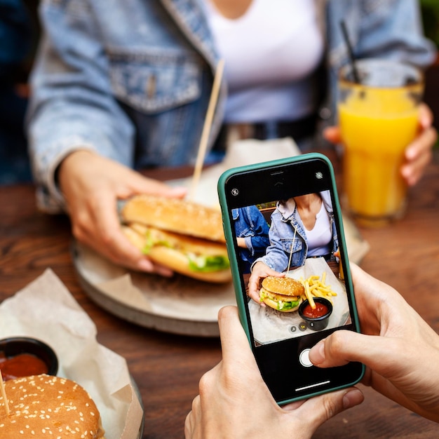 Person taking picture of someone eating burger