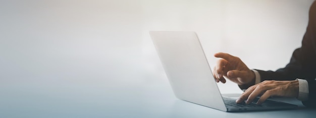 Person typing on laptop keyboard and pointing at screen businessman working on laptop he is typing messages to colleagues and making financial information sheet to sum up the meeting