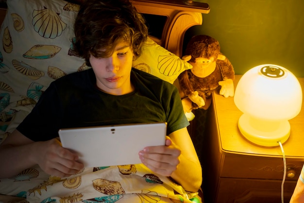 Person use the electronic tablet while lie in bed before sleep b