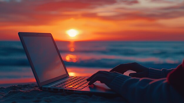 Person using laptop on the beach at sunset