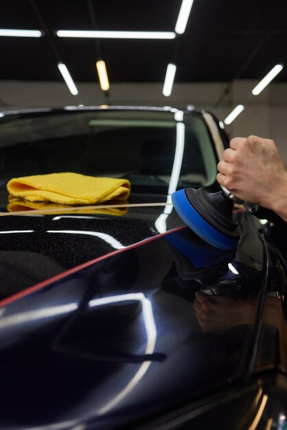 Person using machine to polish black cars automotive exterior