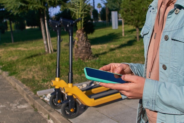 Person using smartphone and mobile app for rental a scooter for fast mobile active riding through the city