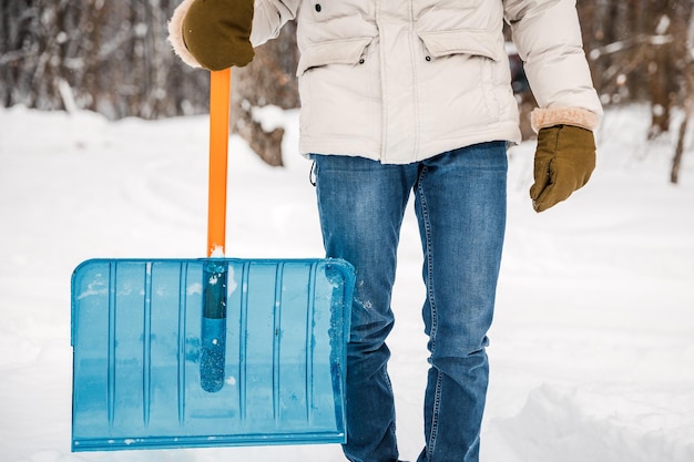 A person using a snow shovel cleans the road or playground from snow