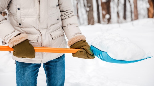 A person using a snow shovel cleans the road or playground from snow