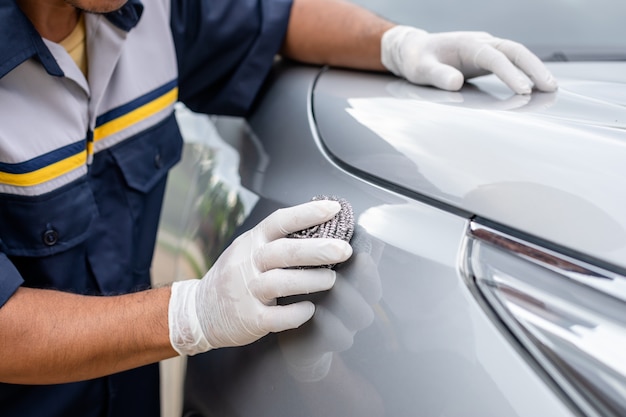 Person using stainless steel wool to polishing the surface of a car