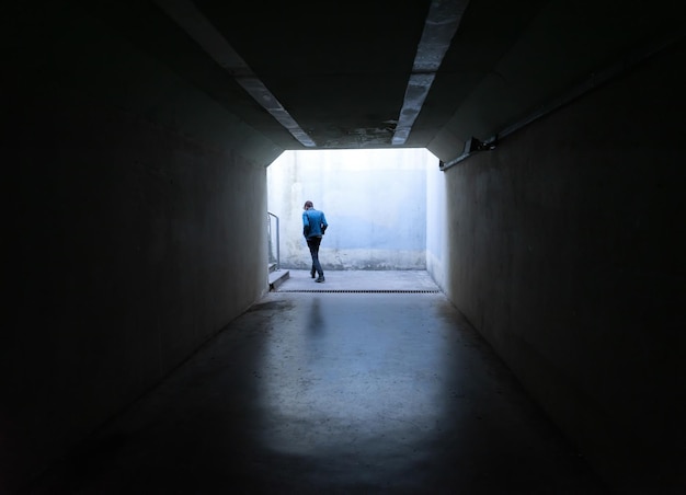 Person walking in dark tunnel exit