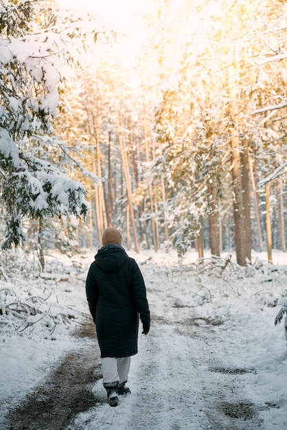 A person walks on the winter road No face woman hiking in a snowcovered forest