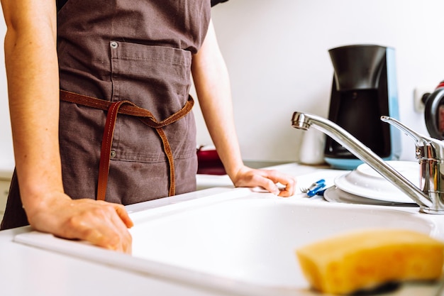 A person washing dishes in a kitchen sink.