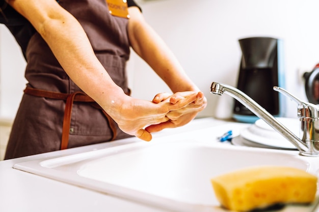 A person washing their hands in a kitchen sink