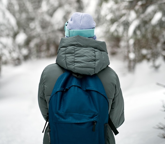 A person wearing a backpack in the snowy outdoor area Back of the woman hiking Concept of solitude adventures in winter mountains