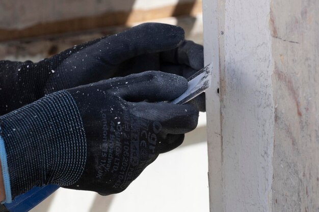 A person wearing a glove is using a piece of wood to cut a piece of wood.