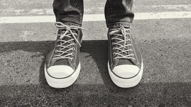 Photo person wearing pair of black laceup sneakers