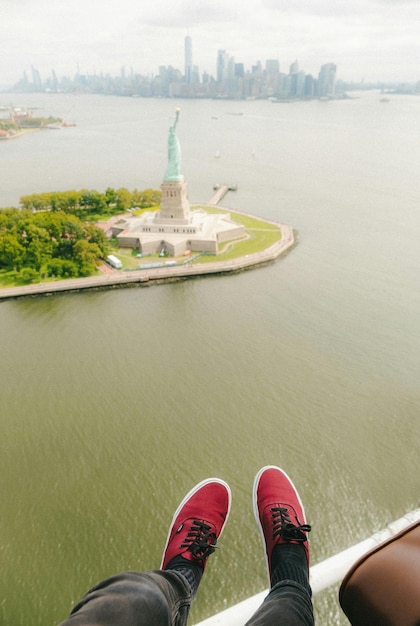 a person wearing red shoes stands in front of a statue of liberty