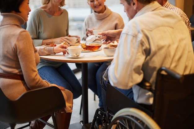 Person with disability man pouring tea to friends