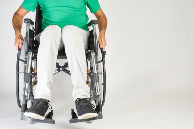 Person with a disability sitting in a wheelchair from the front on a neutral background