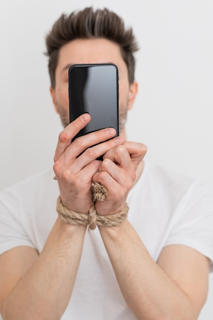 A person with his hands tied holding a smartphone internet addiction or social media addiction