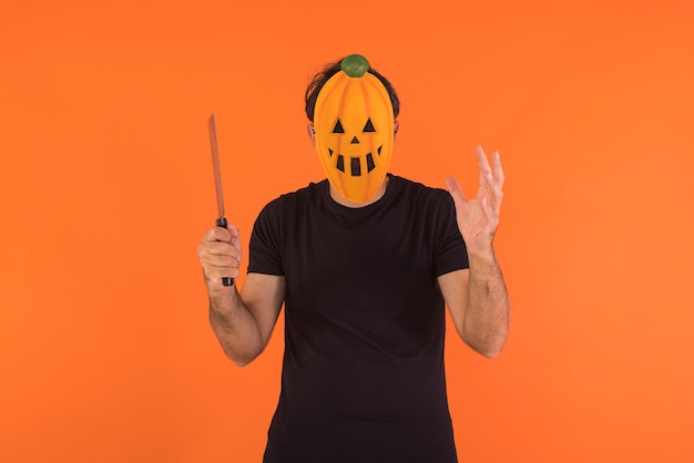 Person with pumpkin mask celebrating Halloween holding a knife raising his hands Concept of celebration All Souls39 Day and All Saints39 Day