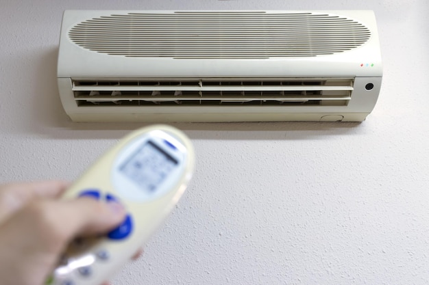 A person with the remote control turns on the air conditioner copia