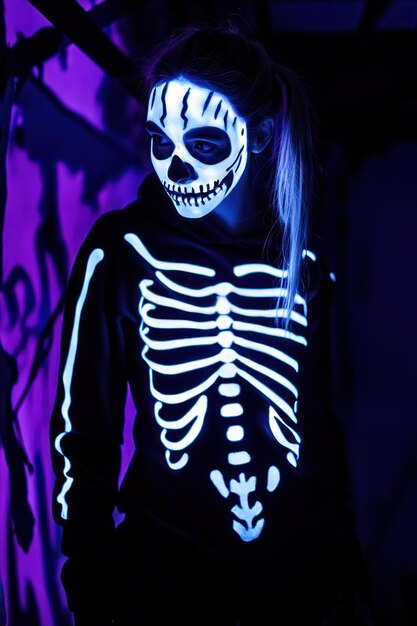 Photo a person with a skeleton face paint and glowing skeleton hoodie in a dark setting