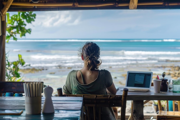 Photo a person working on a laptop at a beachside cafe with an ocean view