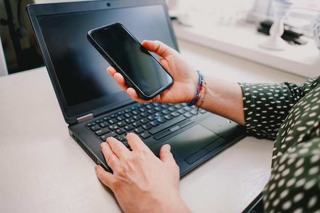 Person working on laptop Business woman working in the office Person holding smart phone in hand