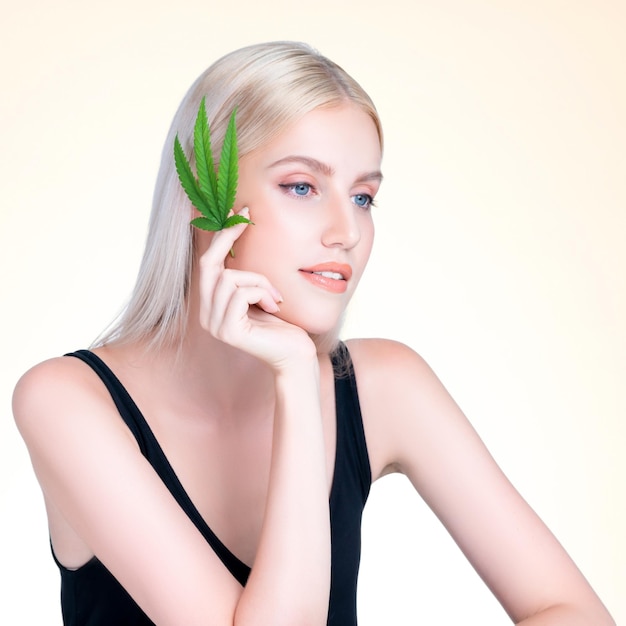 Personable white blond hair woman holding CBD leaf in isolated background