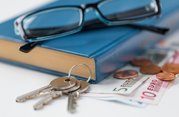 personal stuff and objects concept - close up of book, money, glasses and keys on table