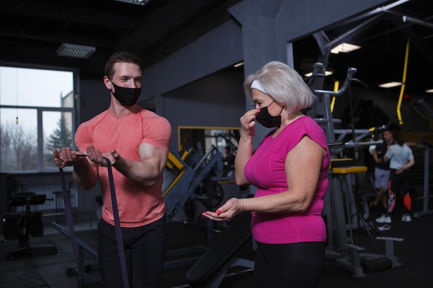 Personal trainer and senior woman wearing face masks exercising during covid19 pandemic