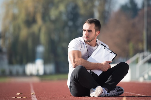 Personal Trainer In Sports Outfit Takes Notes On Clipboard in City Park Area  Training and Exercising for Endurance  Healthy Lifestyle Concept Outdoor