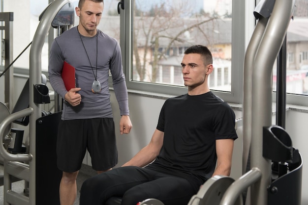 Personal Trainer Takes Notes While Man Exercising Legs